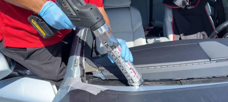 Applying professional urethane sealant during windshield installation in Leander TX